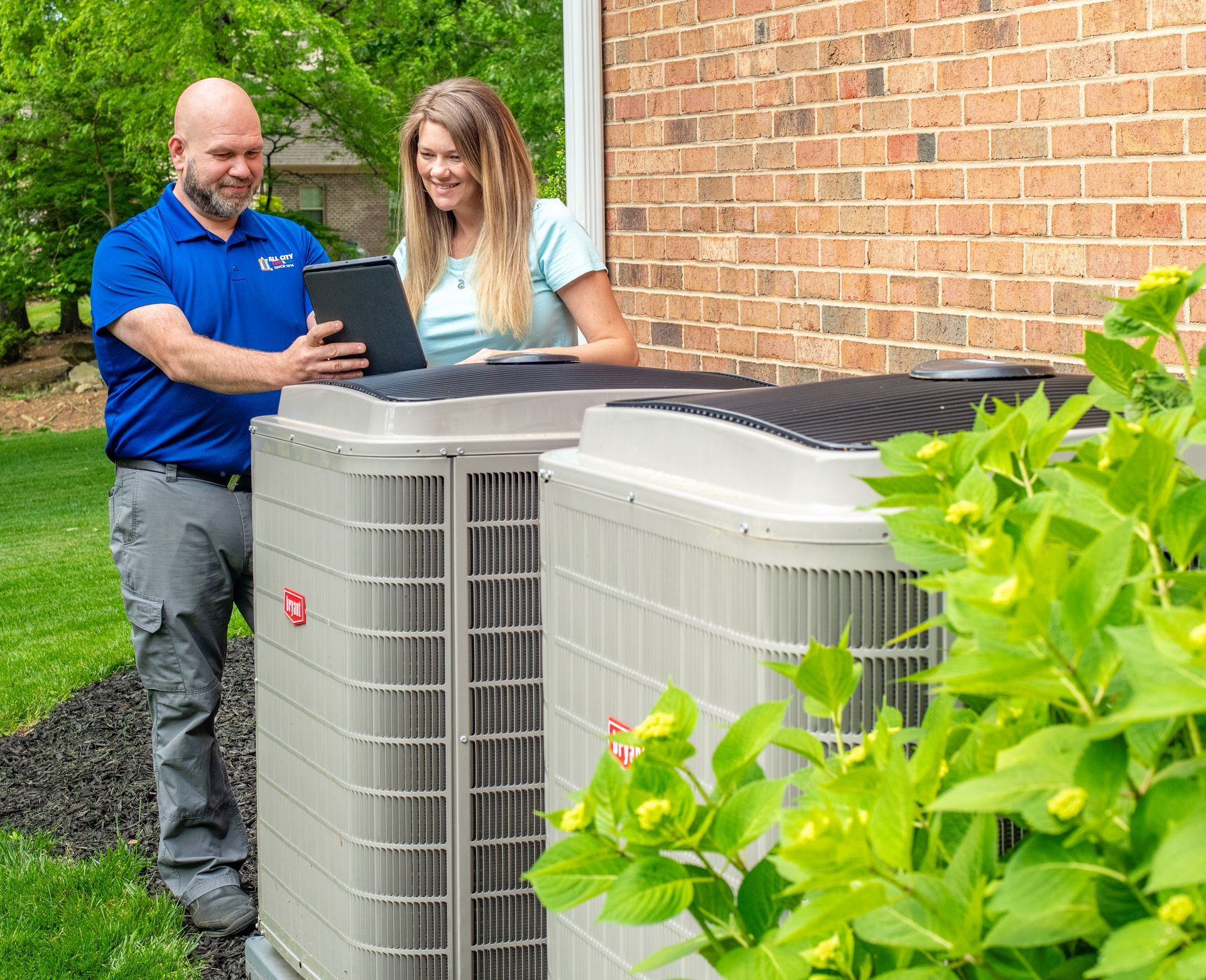 All City Heat and Air technician is working on an air conditioner outside of a house .