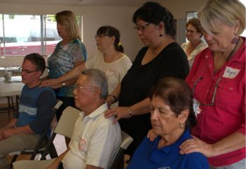 A group of people are sitting in chairs and one woman is wearing a name tag that says angela