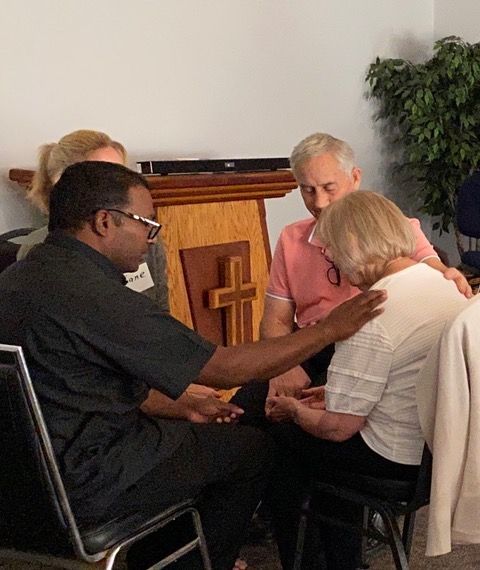 A group of people are sitting in a circle with a cross in the background