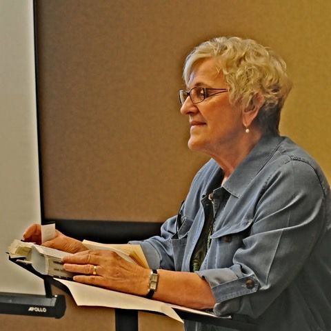 A woman in a blue shirt is sitting in front of a pole