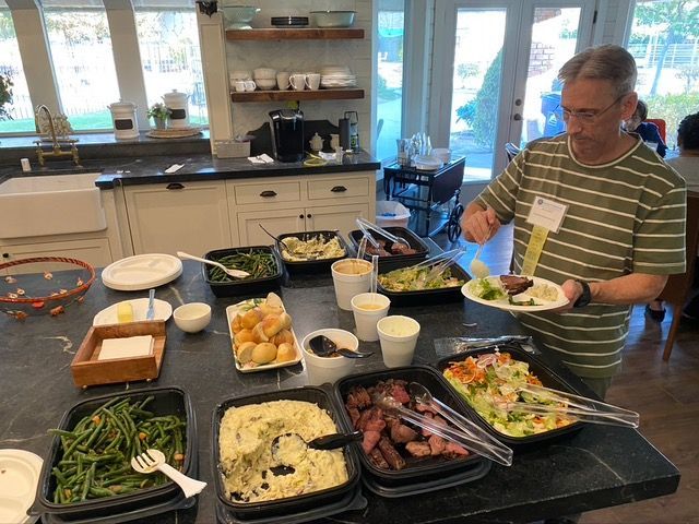A man is standing at a buffet table with plates of food.