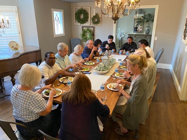 A group of people are sitting around a long table eating food.