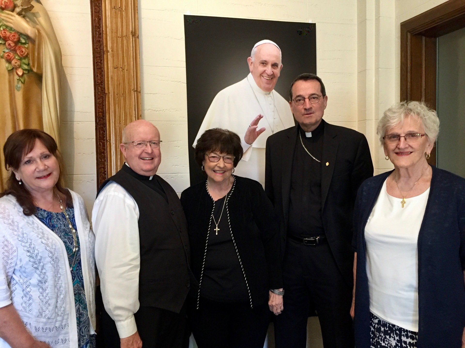 A group of church leaders posed in front of a portrait of the pope.