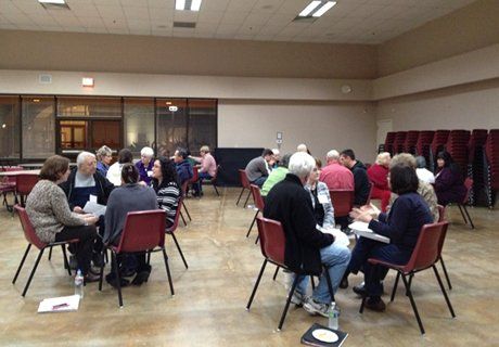 A group of people are sitting around tables in a room