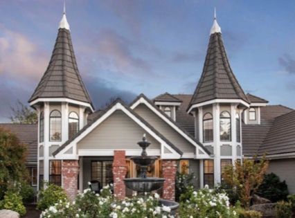A large house with two towers and a fountain in front of it