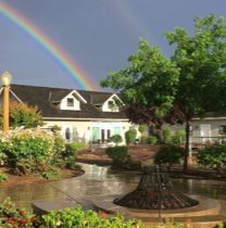 There is a rainbow in the sky over a house.