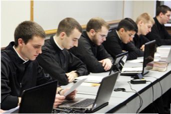 A group of men are sitting at a table with laptops.
