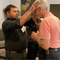 A church leader laying hands on a man in prayer.