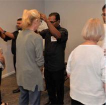 A group of people are standing in a room talking to each other.