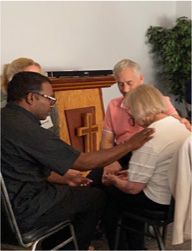 A group of people are sitting in a circle in front of a cross.