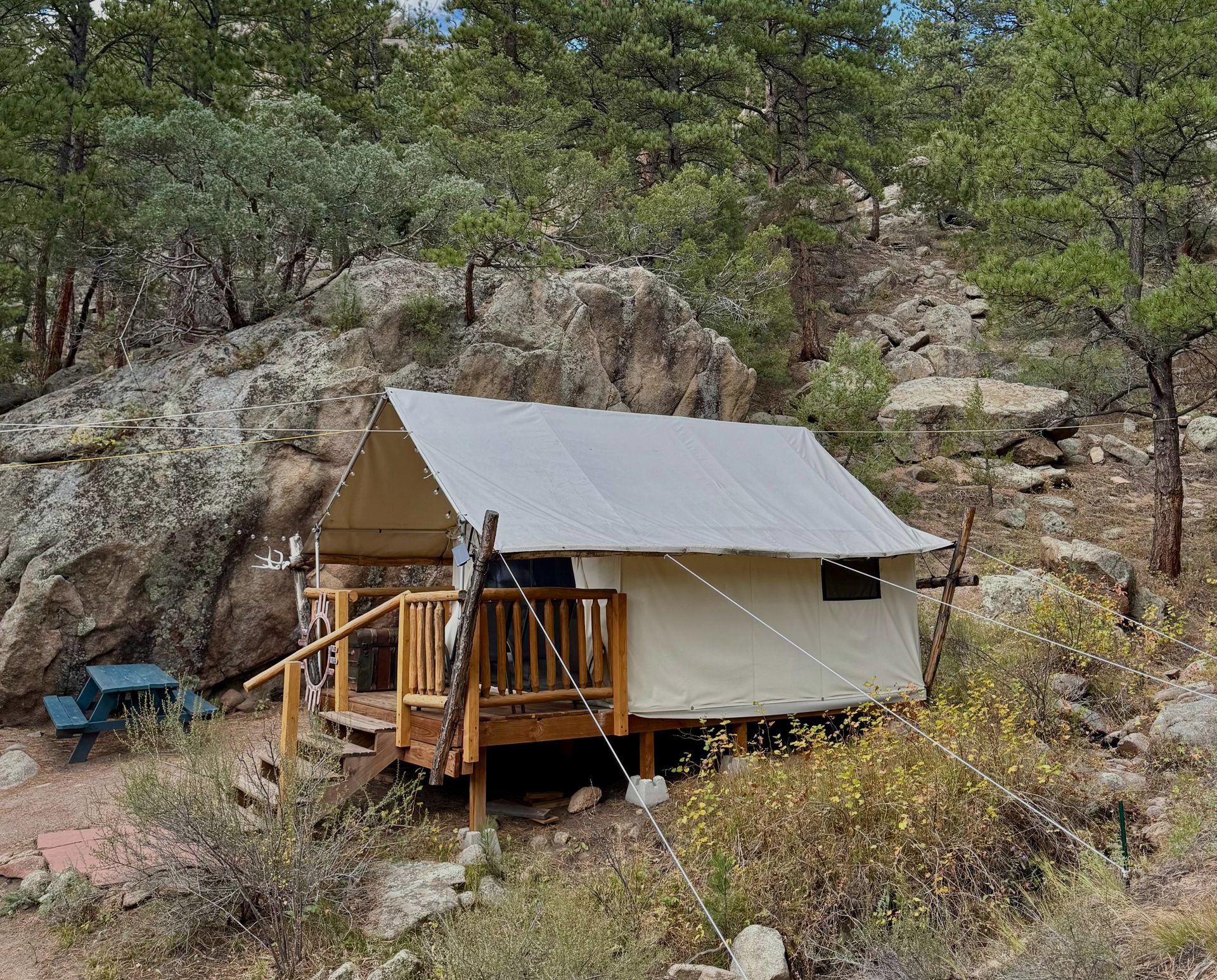 Canvas tent on wooden platform near large rocks and trees.