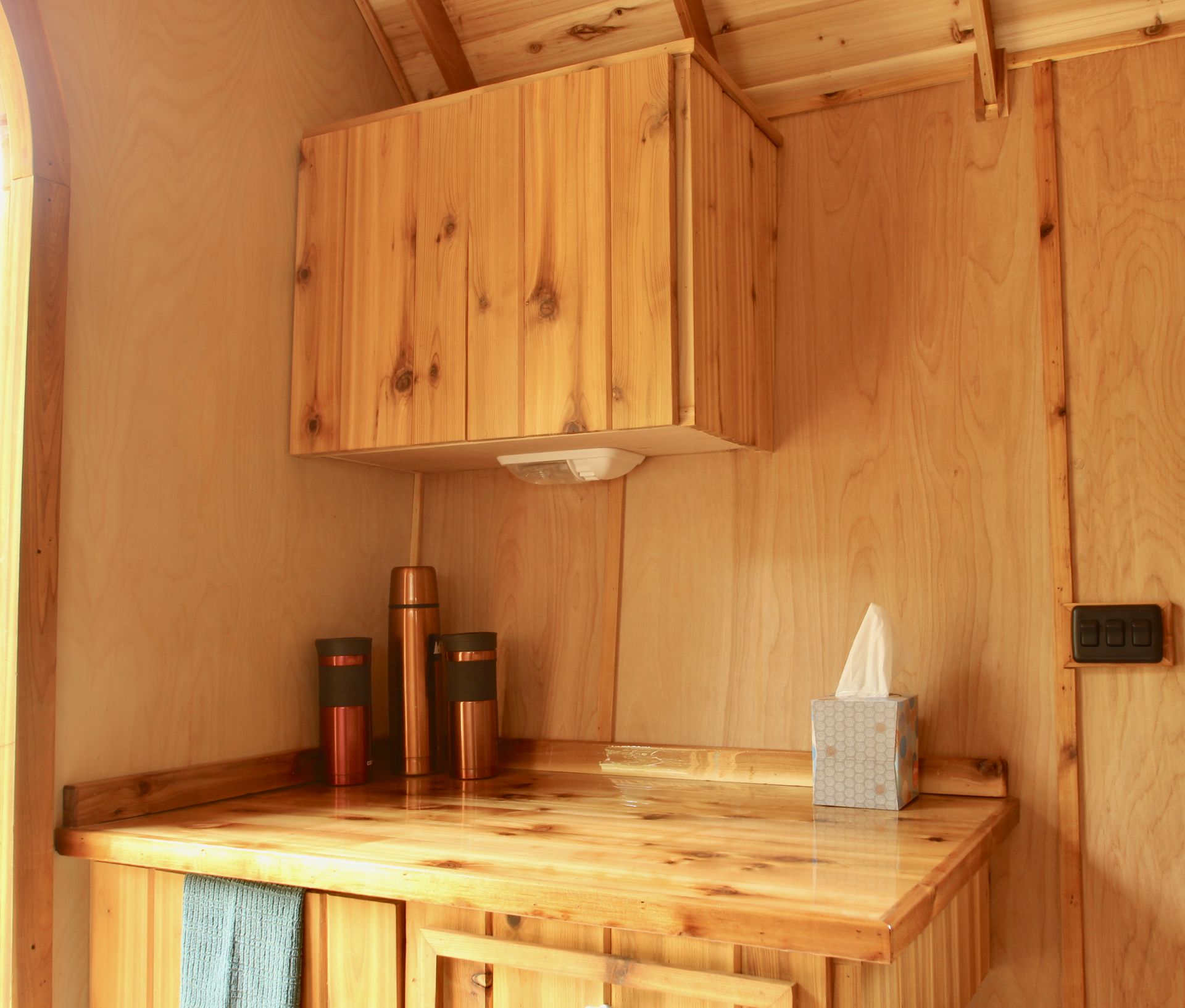 Wooden cabin interior with countertop, cabinets, and tissue box.