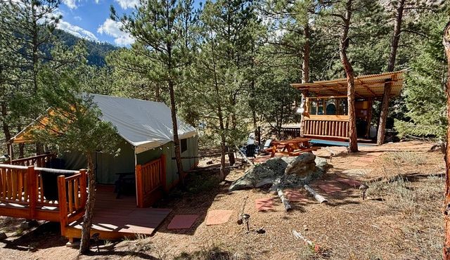 Two cabins with wooden decks nestled among trees; forest setting.