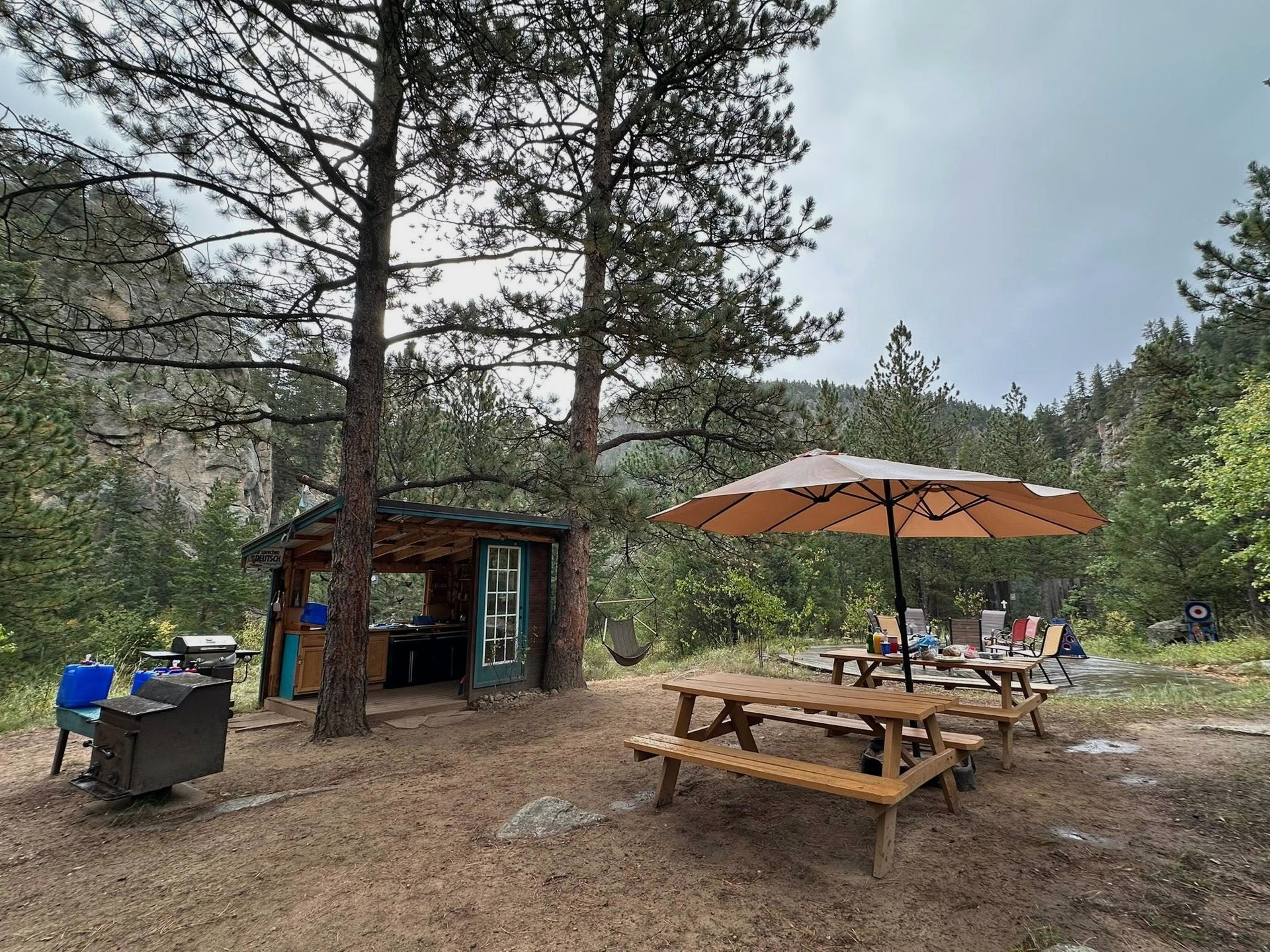 Camping area with picnic tables, a shelter, and trees in a canyon.