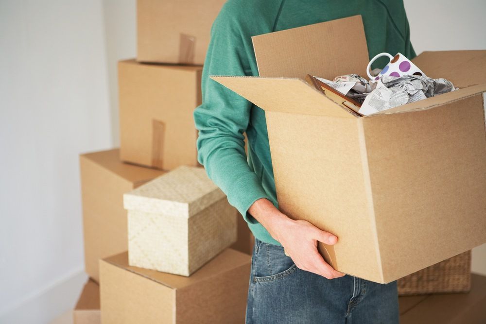 A Man is Carrying a Cardboard Box — AKM Self Storage In Kurri Kurri, NSW