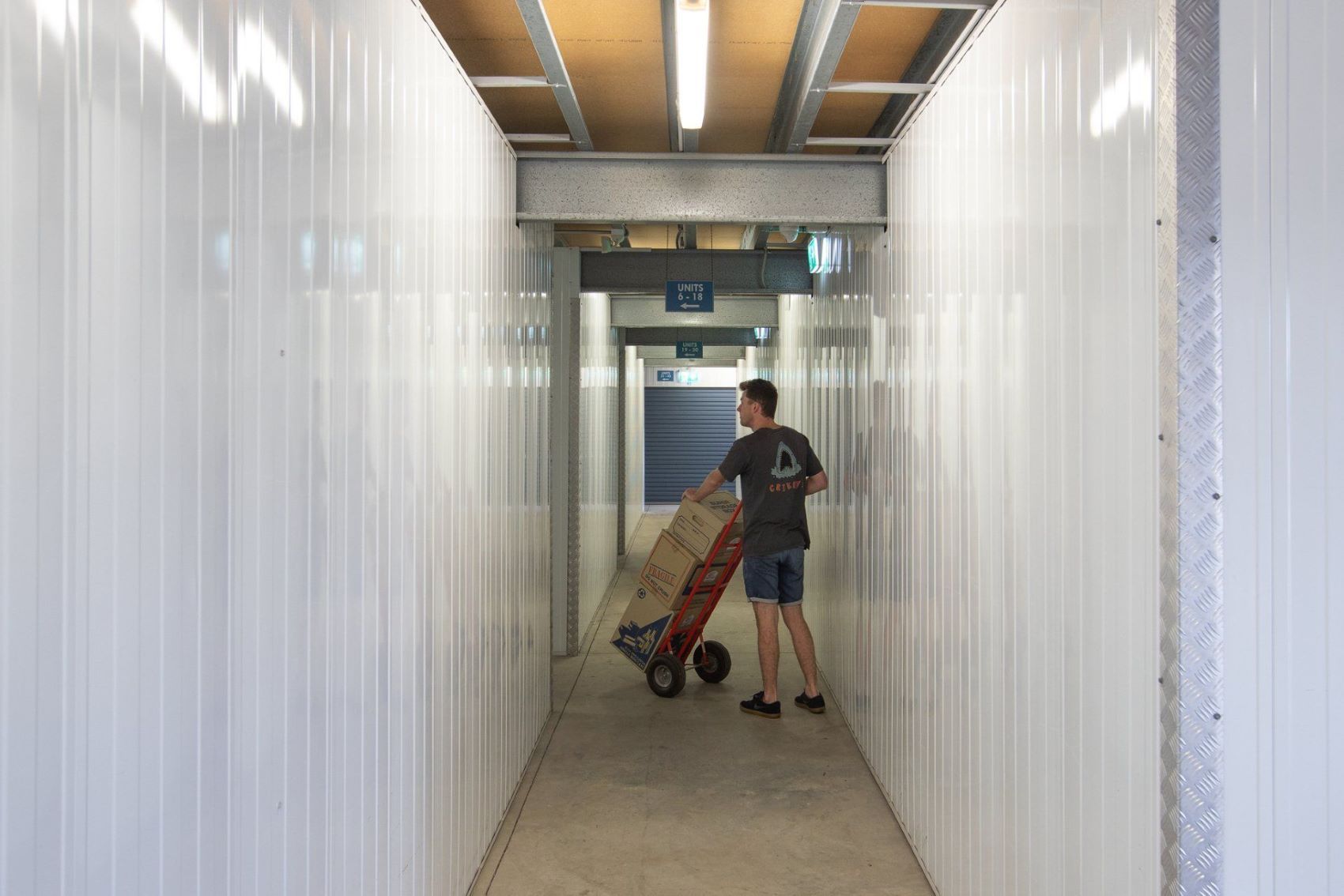 A Man is Pushing a Cart of Boxes Down a Hallway — AKM Self Storage In Kurri Kurri, NSW