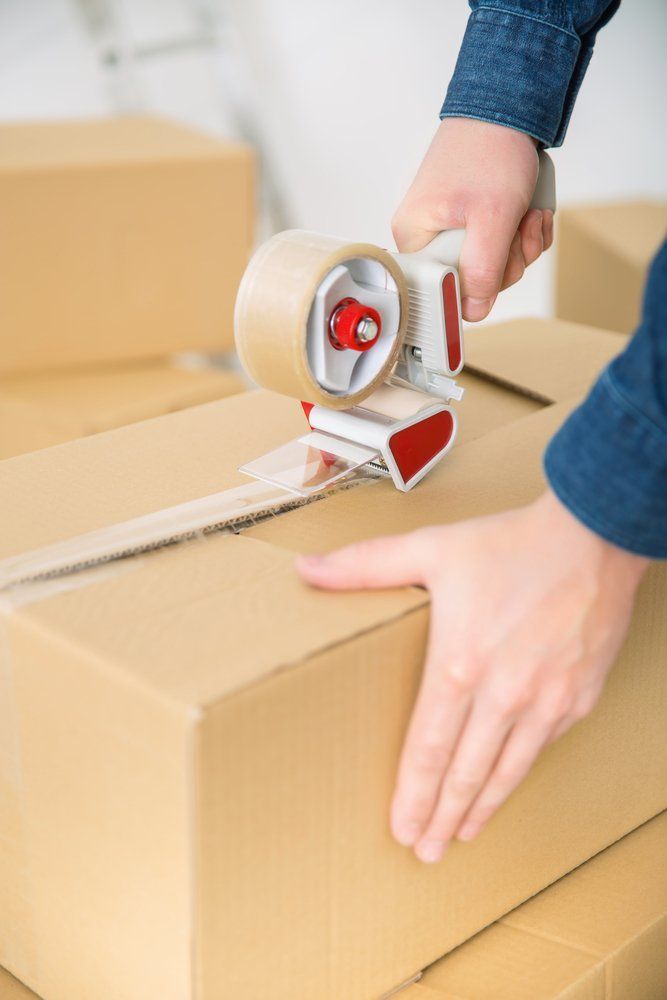 A Person is Taping a Cardboard Box With Tape — AKM Self Storage In Kurri Kurri, NSW