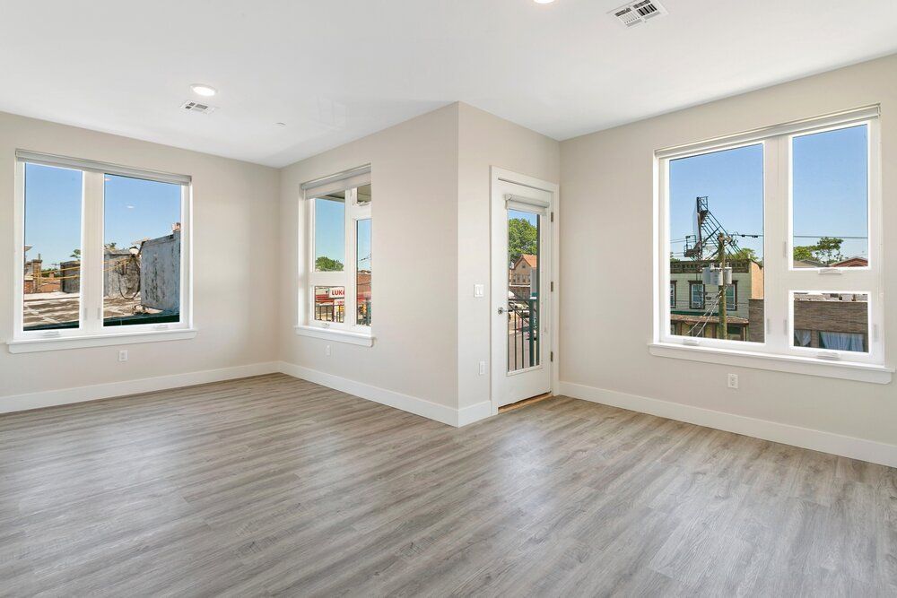 An empty living room with hardwood floors and lots of windows.