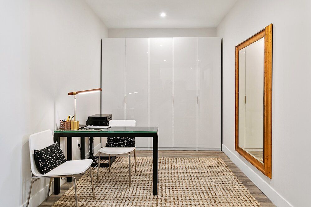 A room with a desk and chairs and a mirror on the wall