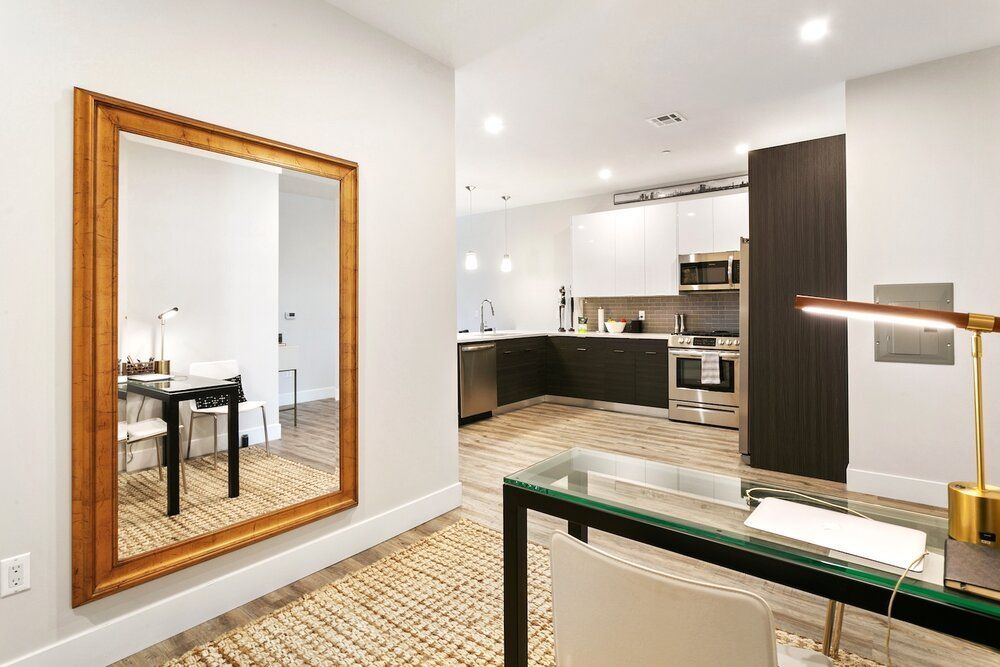 A large mirror is hanging on a wall next to a desk in a living room.