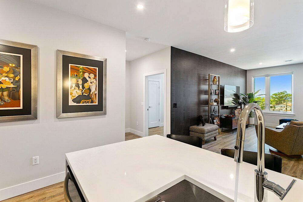 A kitchen with a sink , faucet and paintings on the wall.