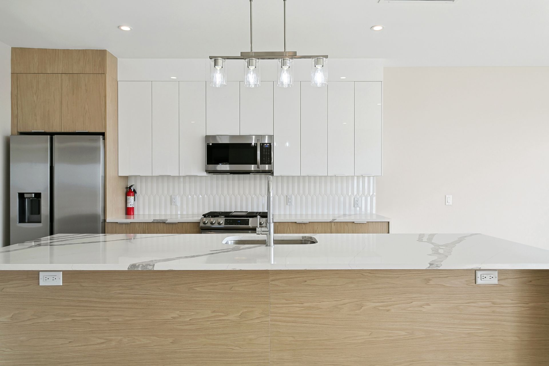 A kitchen with white cabinets , stainless steel appliances , and a large island.