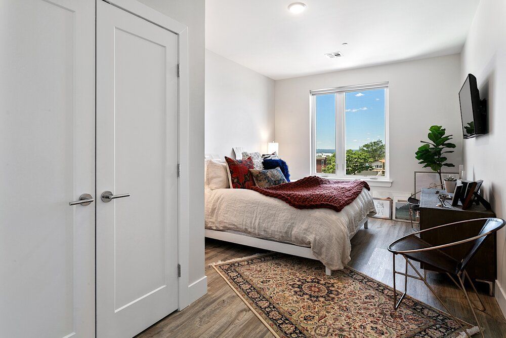 A bedroom with a large bed , rug , chair and television.