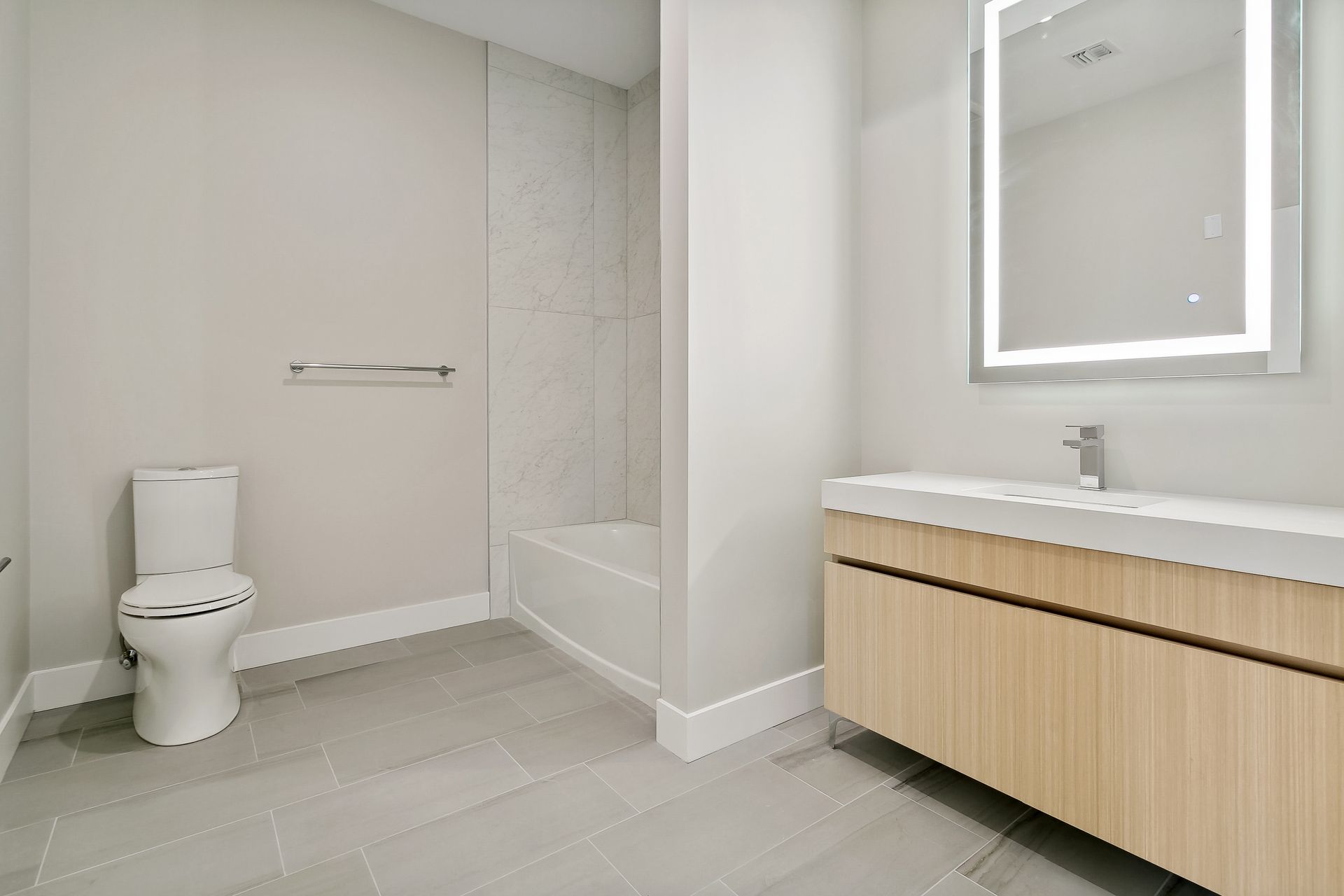 A bathroom with a toilet , sink and mirror.