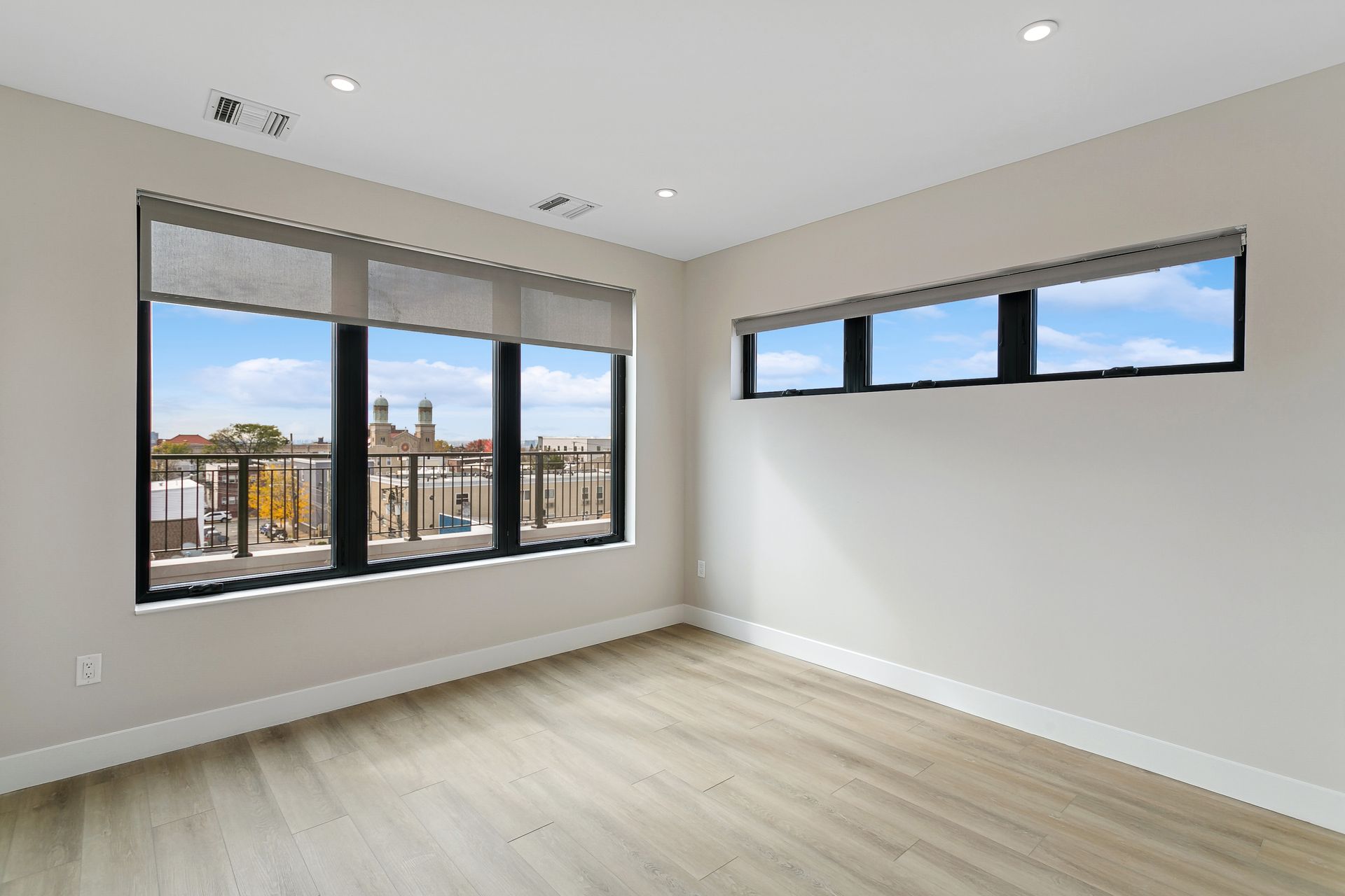 An empty room with two large windows and a balcony.