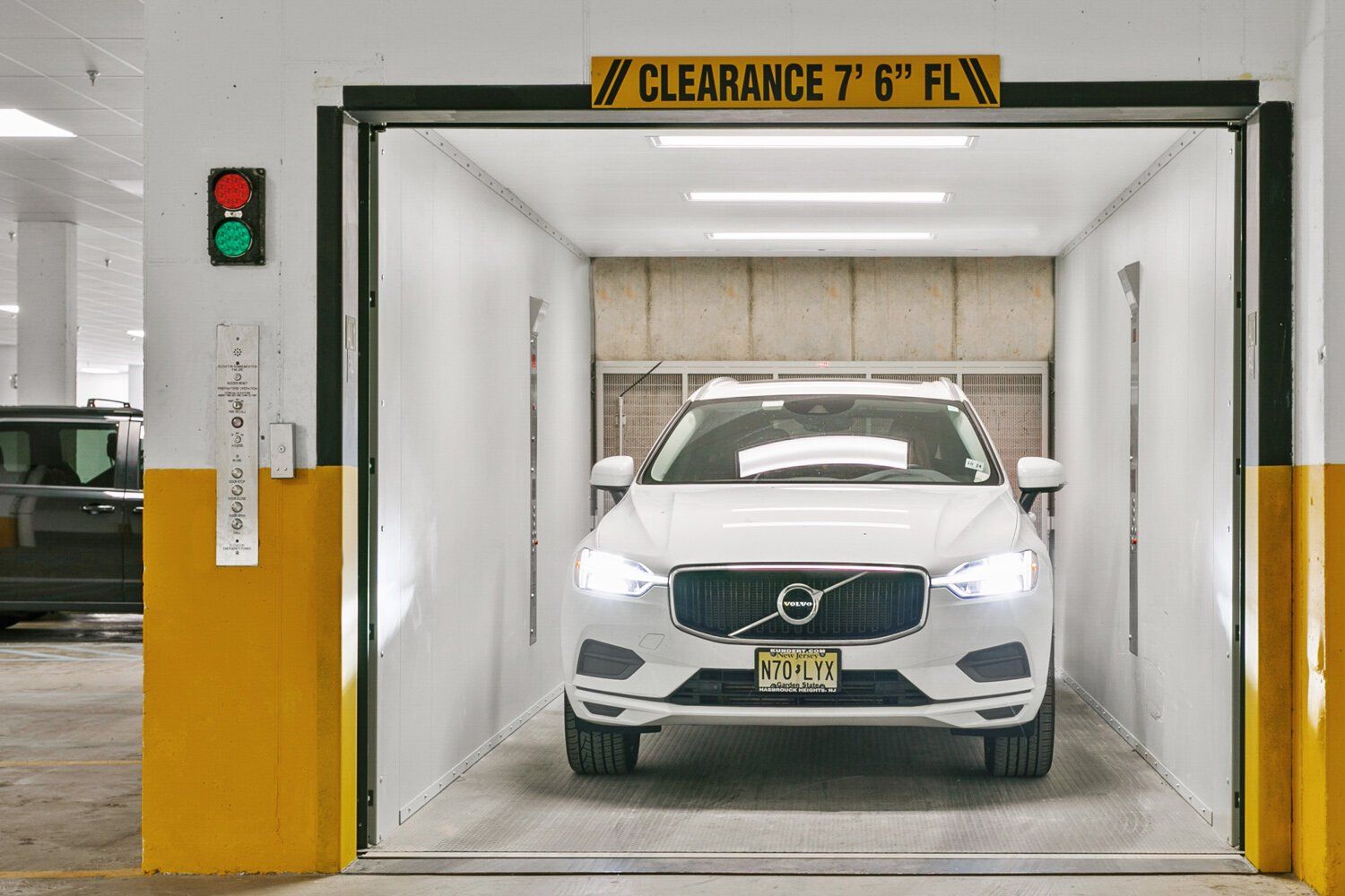 A white volvo is parked in a clearance garage.