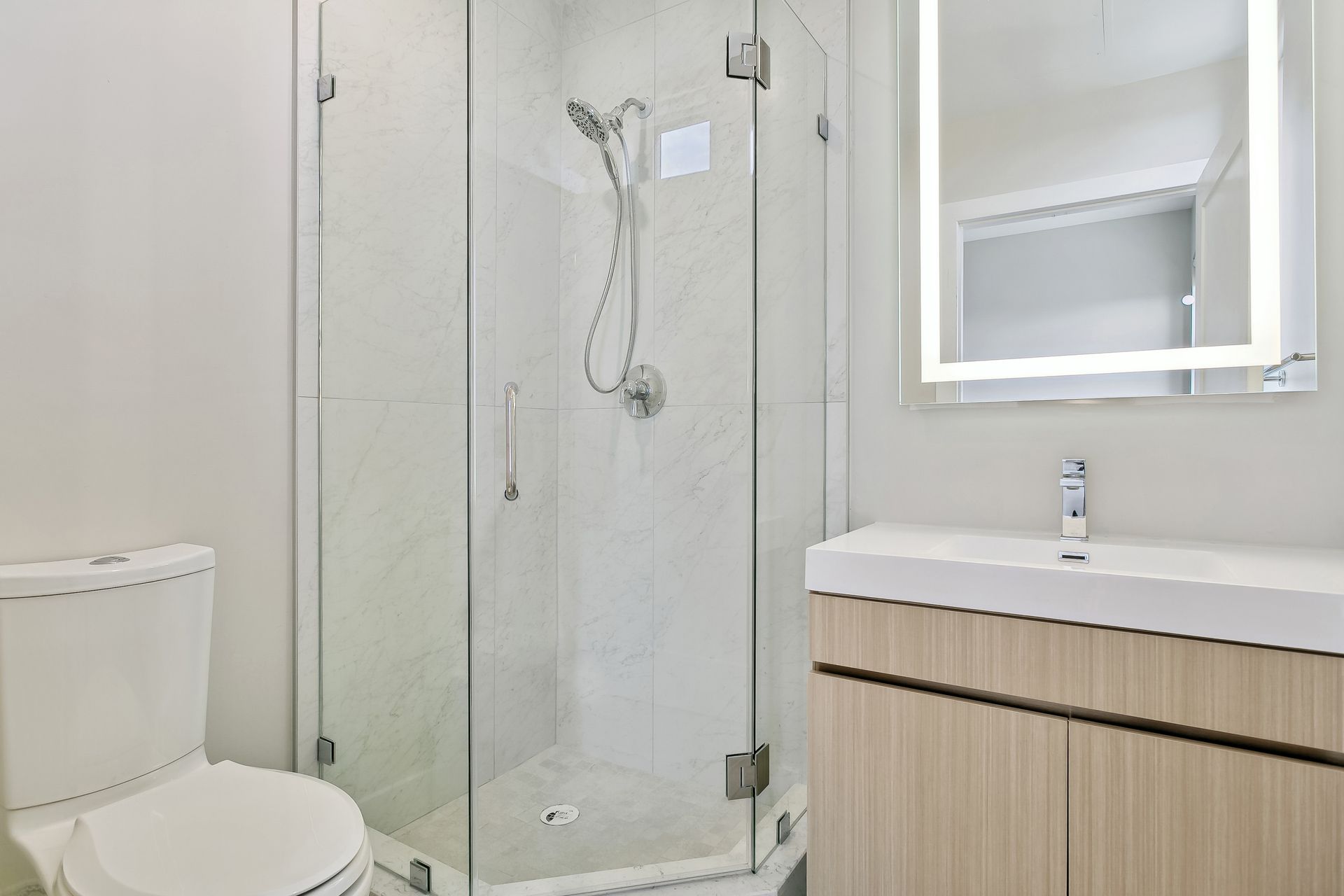 A bathroom with a toilet , sink , shower and mirror.