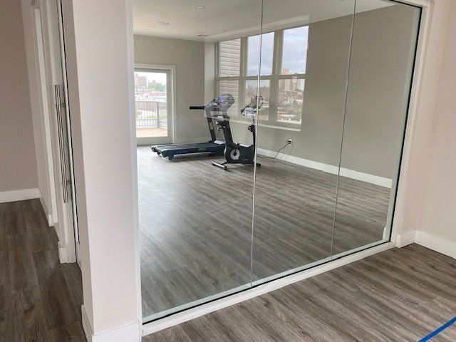 A room with a treadmill and a mirror on the wall.