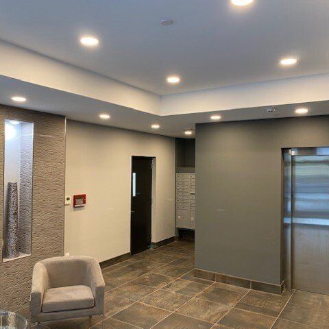 A living room with a chair and a stainless steel elevator.