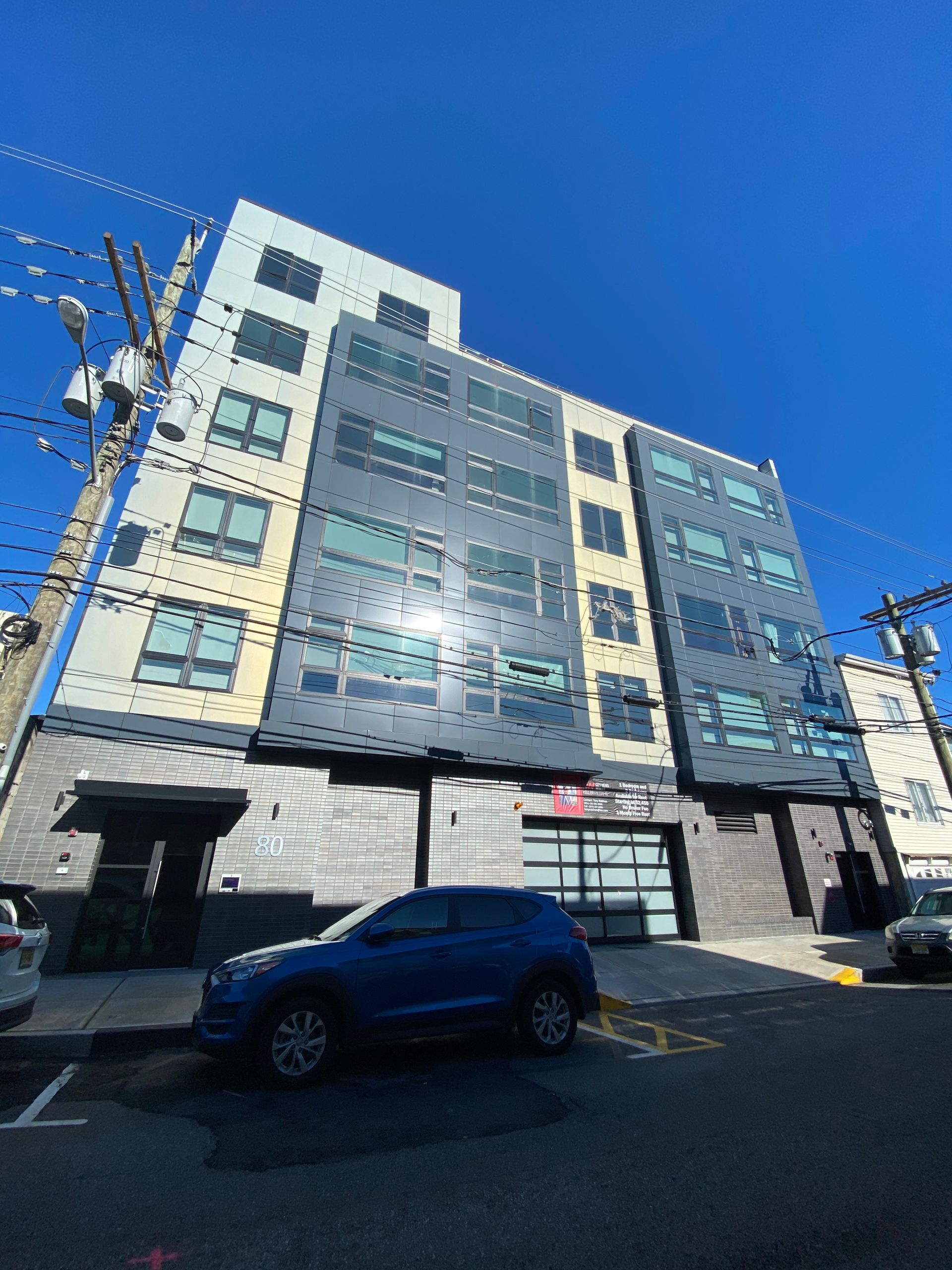 A blue car is parked in front of a tall building.