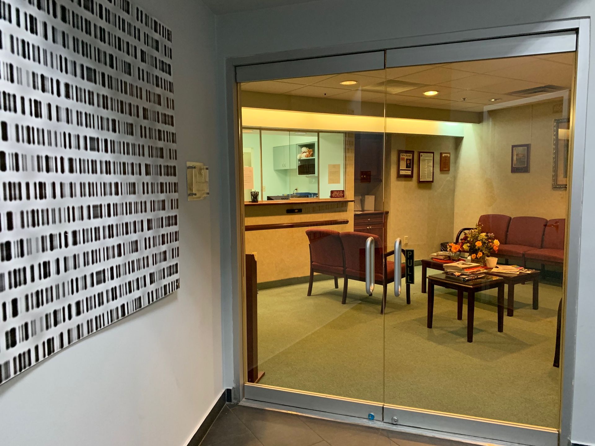 A waiting room with a table and chairs and a glass door