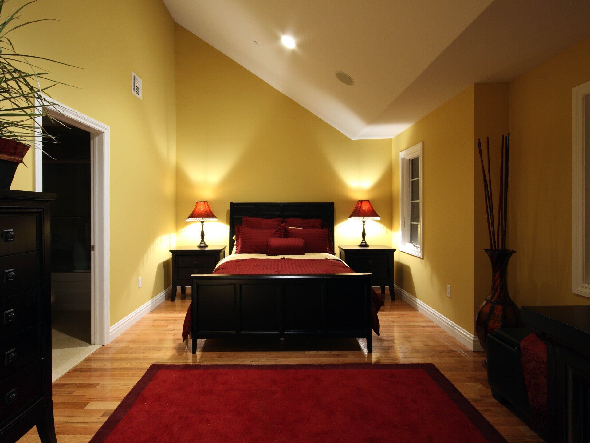 A bedroom with yellow walls and a red rug