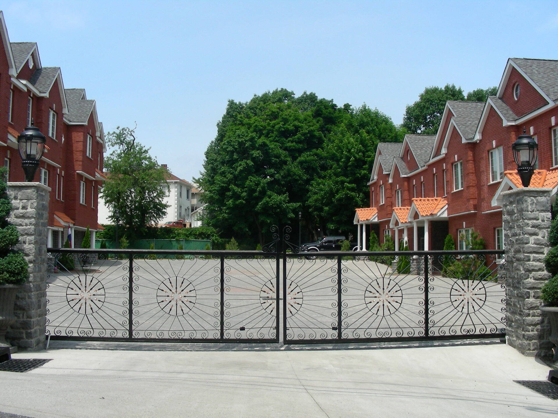 A gated driveway leading to a row of red houses