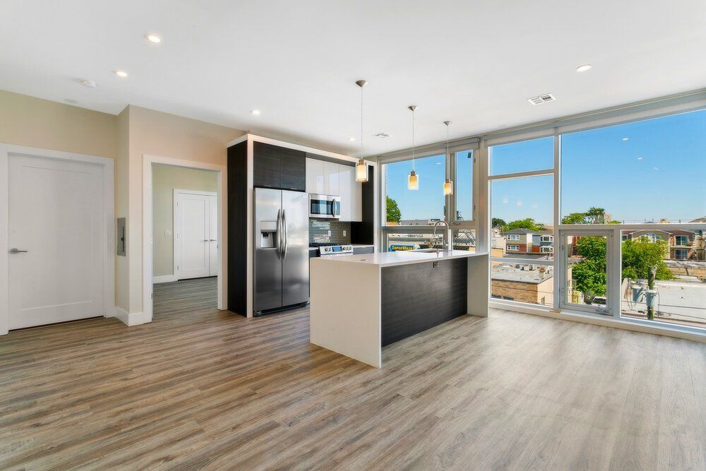 An empty apartment with a kitchen and a large window.