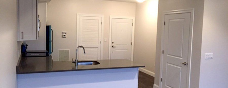 A kitchen with a sink , cabinets , and a door.