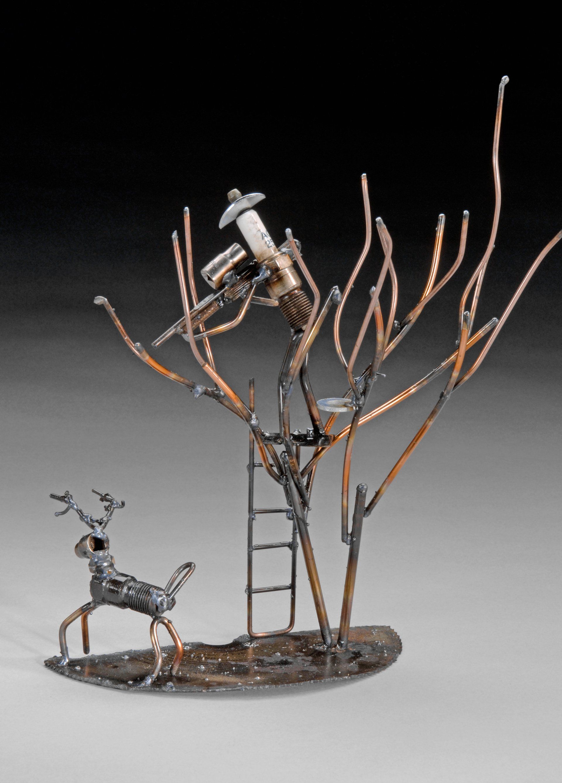 Sparkplug Sculpture of Deer Hunter in a Stand in tree with deer below