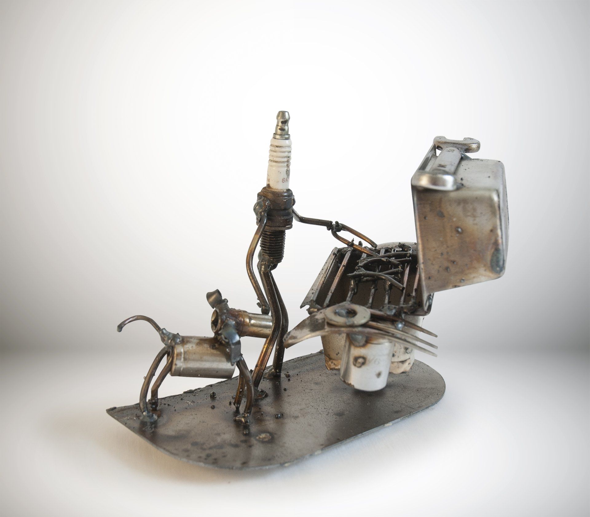 Sparkplug Sculpture - Figure grilling on gas grill with dog at its side