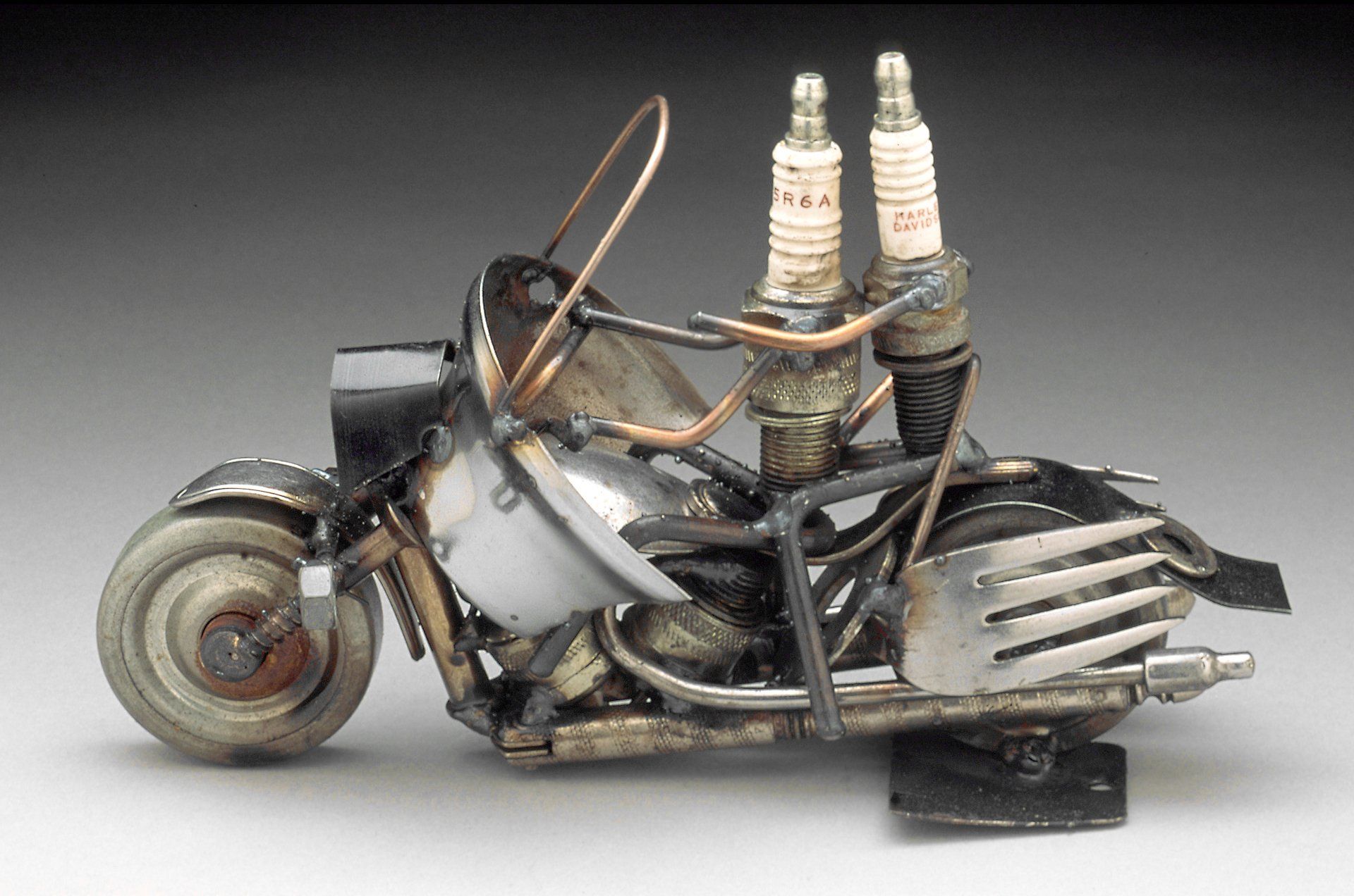Vintage nutcracker with metal rollerskate wheels, forks for bags and genuine Harley Davidson sparkplugs as driver and rider. Can be made with 1 or 2 people and a sidecar or trike. $75