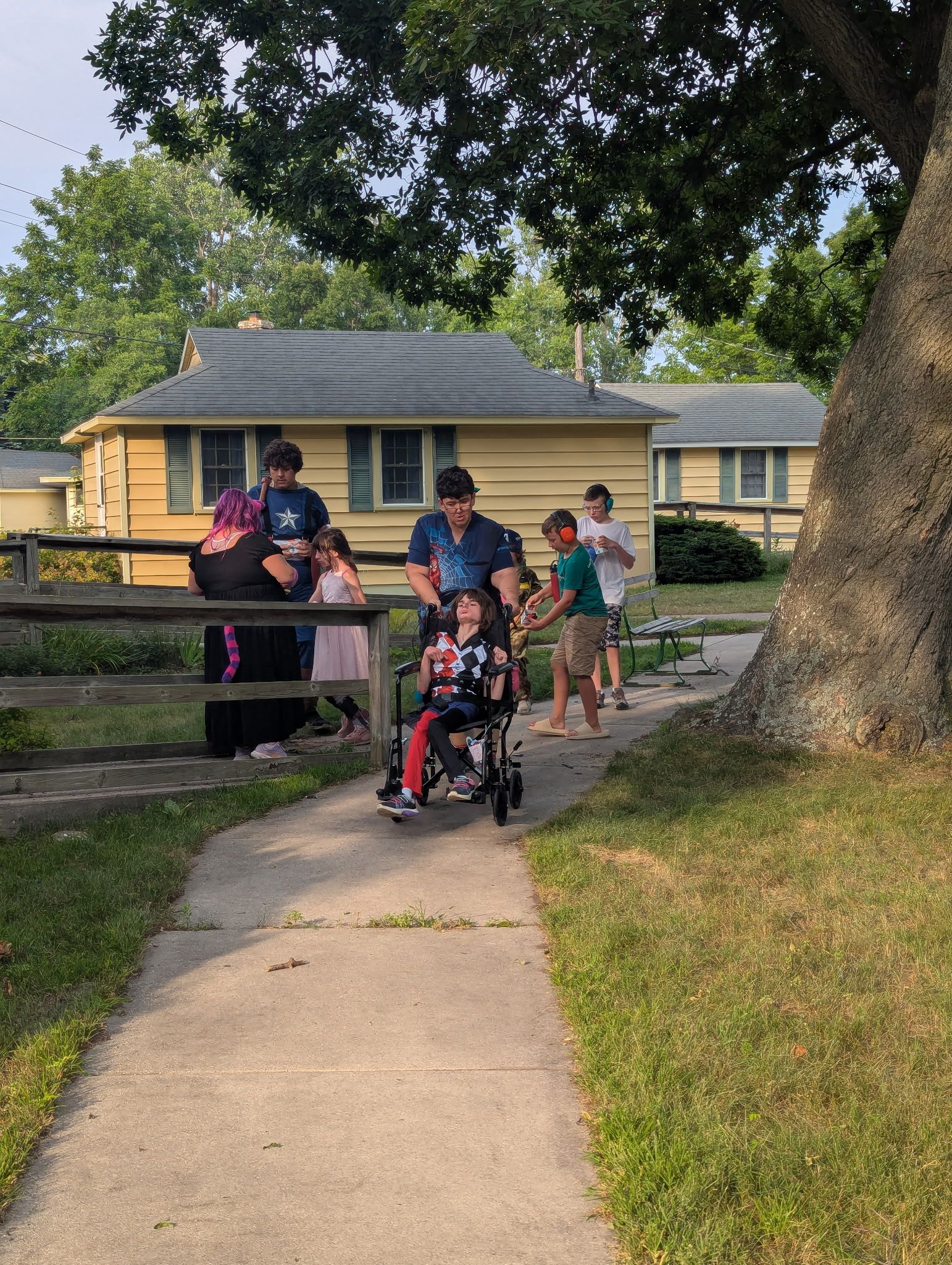 Smiling person surrounded by a group of people in an outdoor setting. Others are wearing park staff uniforms.