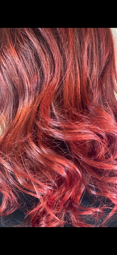 Primo piano di capelli ondulati, castano-rossicci, con riflessi più chiari.