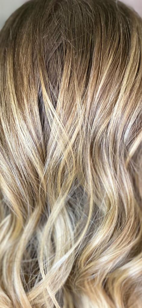 Primo piano di capelli biondi ondulati con mèches castane.