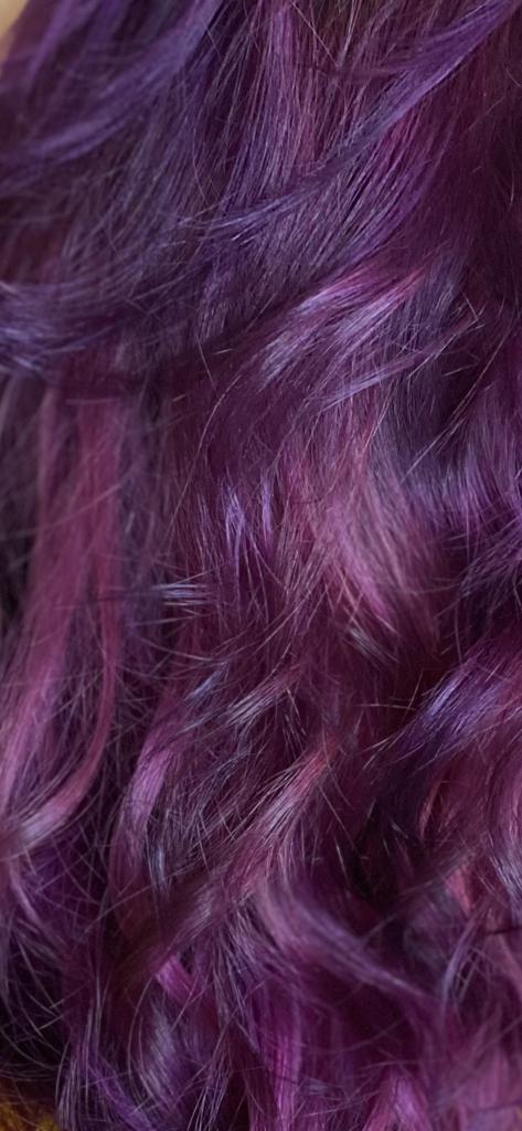 Primo piano di capelli ondulati, di un vivace colore viola e rosa.