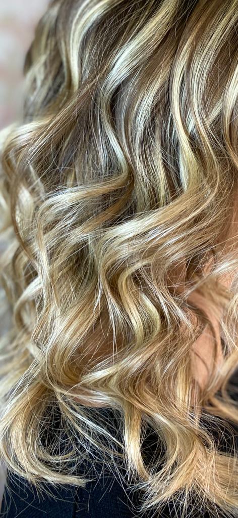 Primo piano di capelli ondulati, chiari, con riflessi biondi.