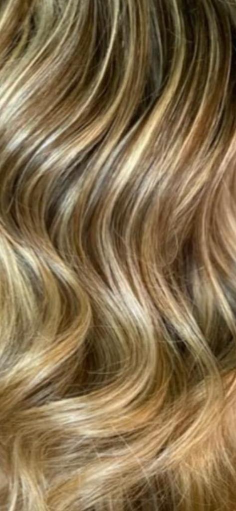 Primo piano di capelli ondulati, castano chiaro con riflessi biondi.