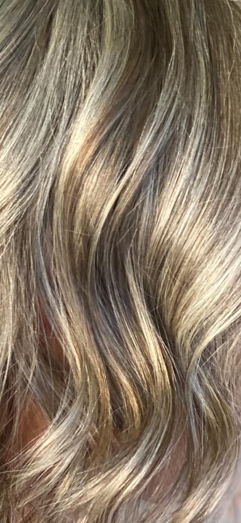 Primo piano di capelli ondulati e chiari con colpi di sole e sfumature.