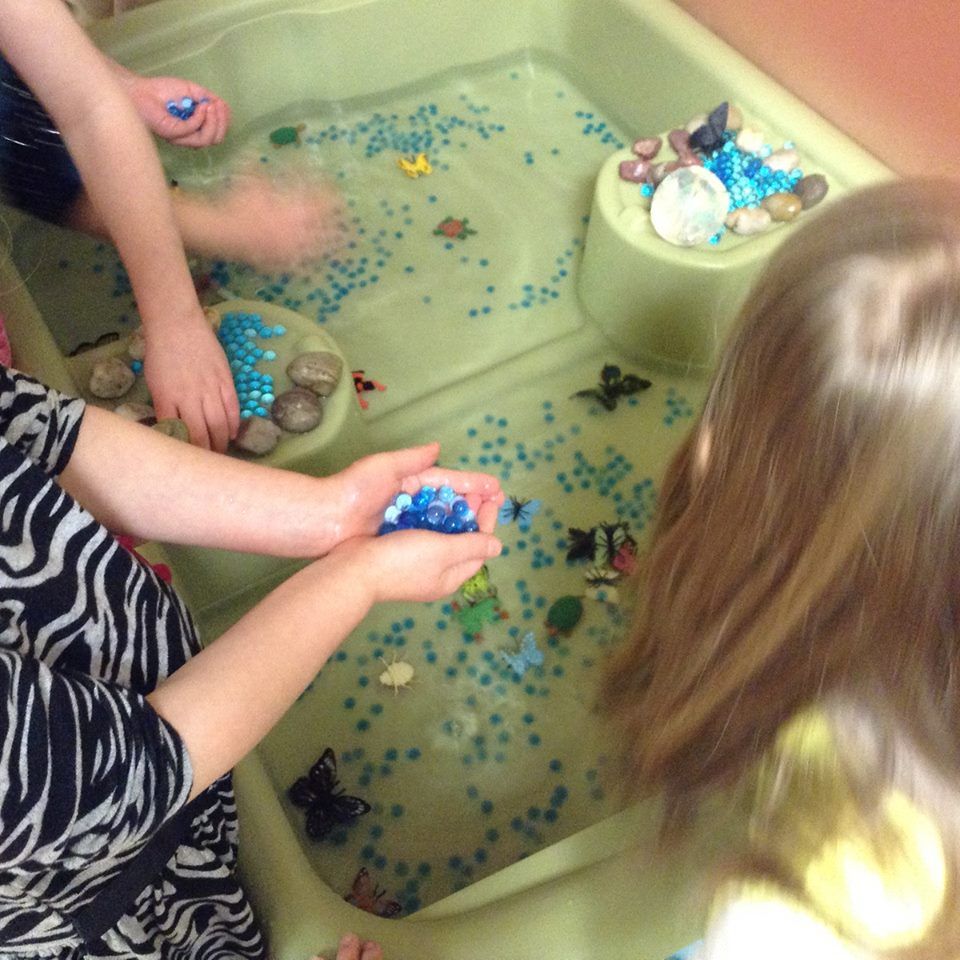 Two children are playing in a bathtub filled with water and rocks